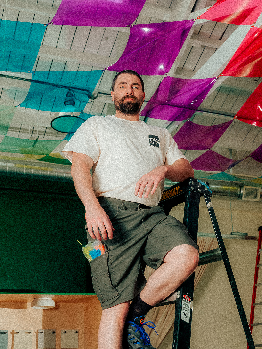 Sheki Cicelsky on a ladder beneath an installation in progress