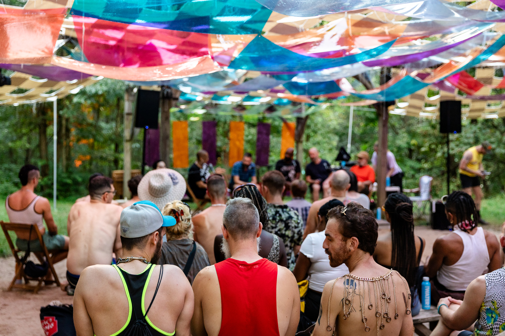 A crowd gathered for a panel discussion beneath the canopy in the woods