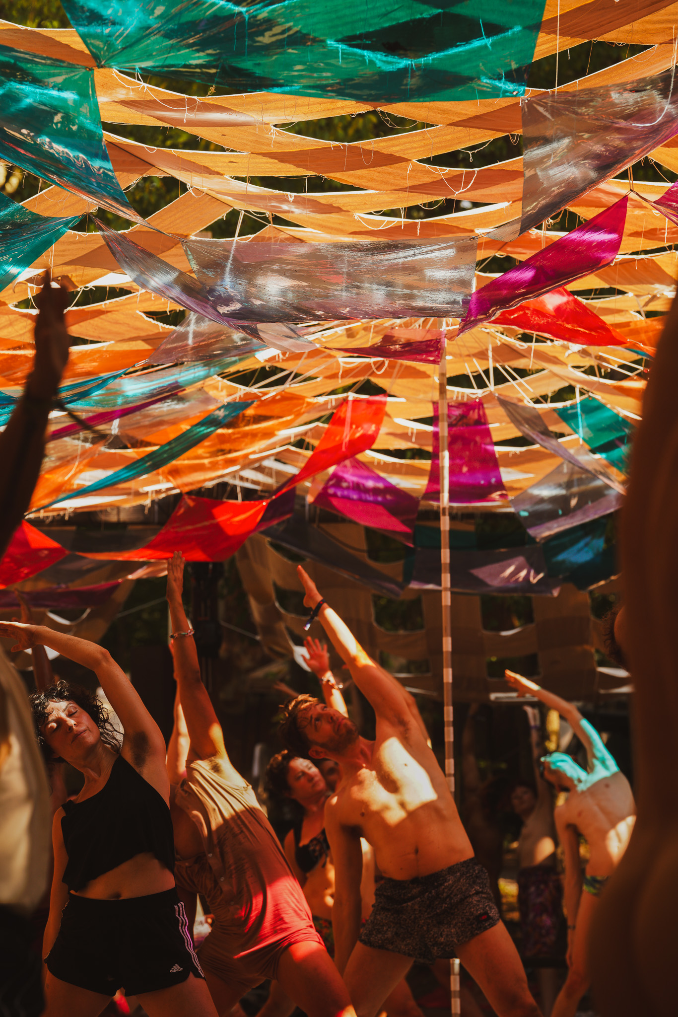 A yoga class stretching beneath sunlit panels of colored vinyl