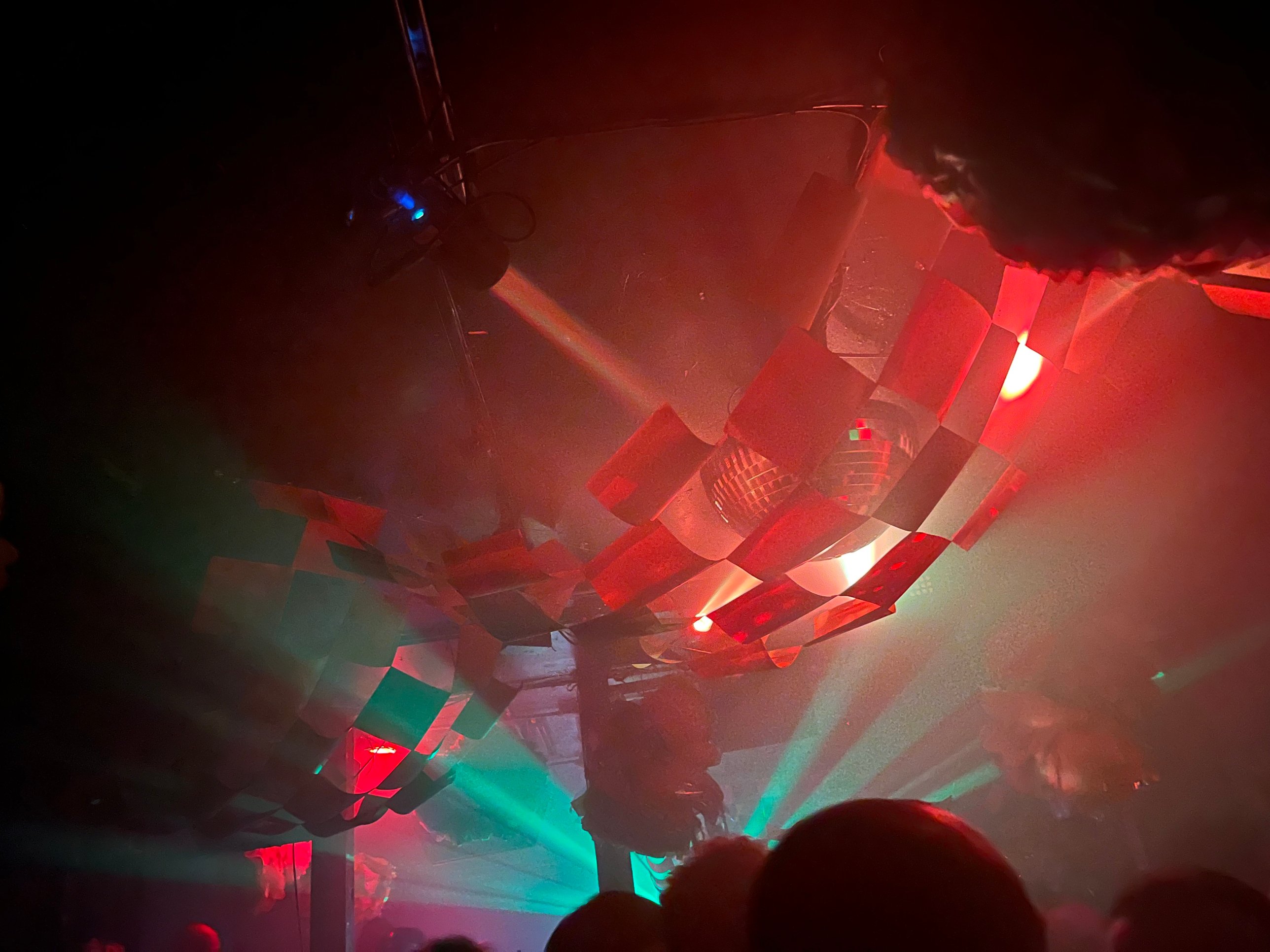 The checkered cardstock canopy wrapped around a mirror ball, lit red with green beams below