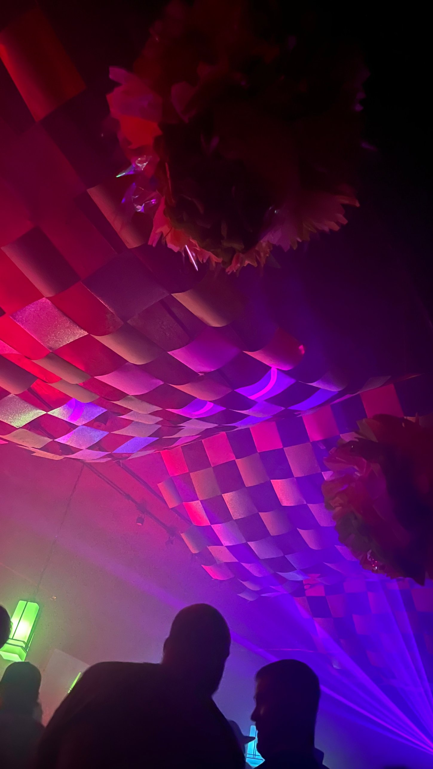 The canopy glowing pink and purple above silhouetted dancers