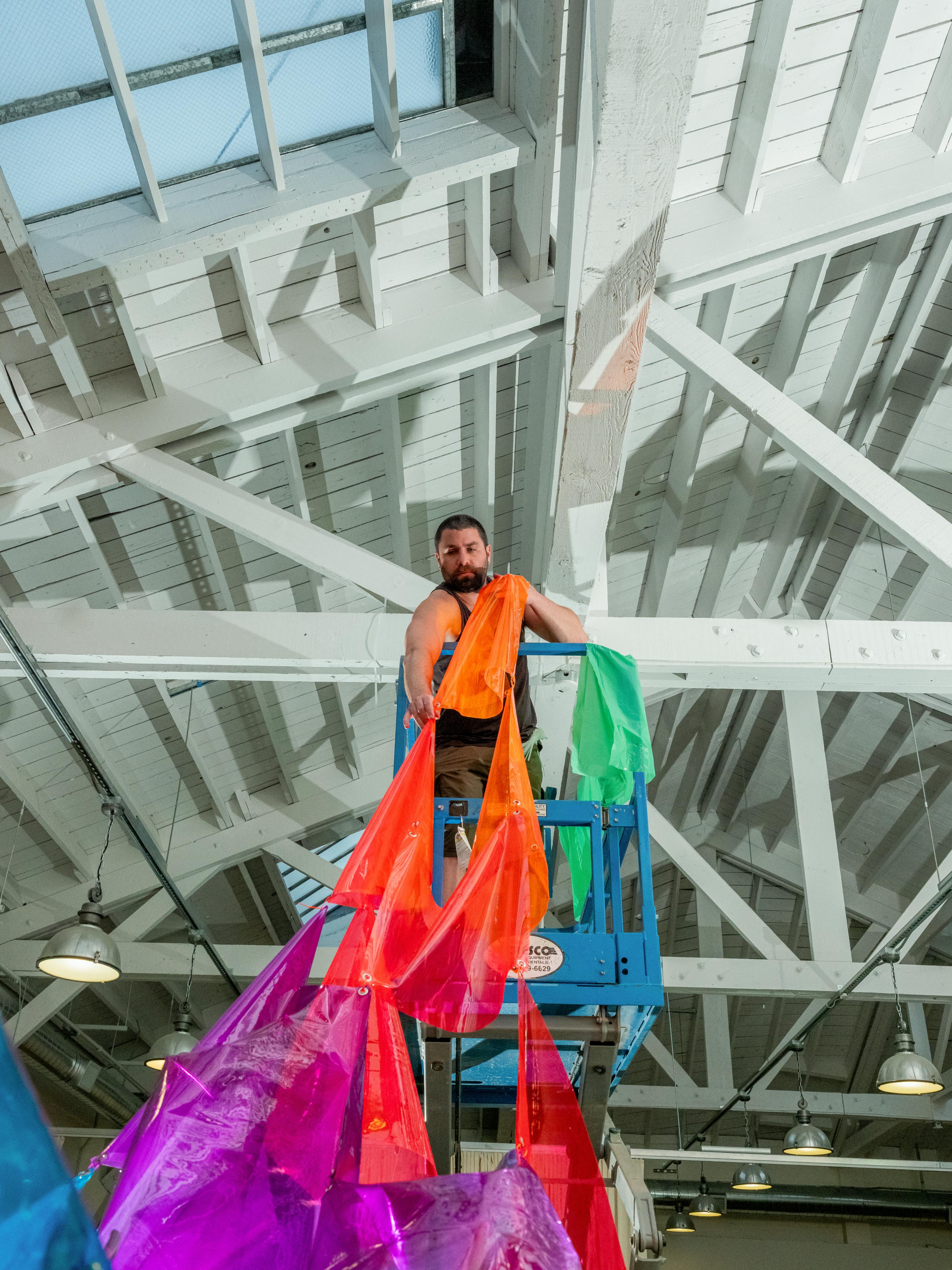 Artist on a lift hanging translucent film panels