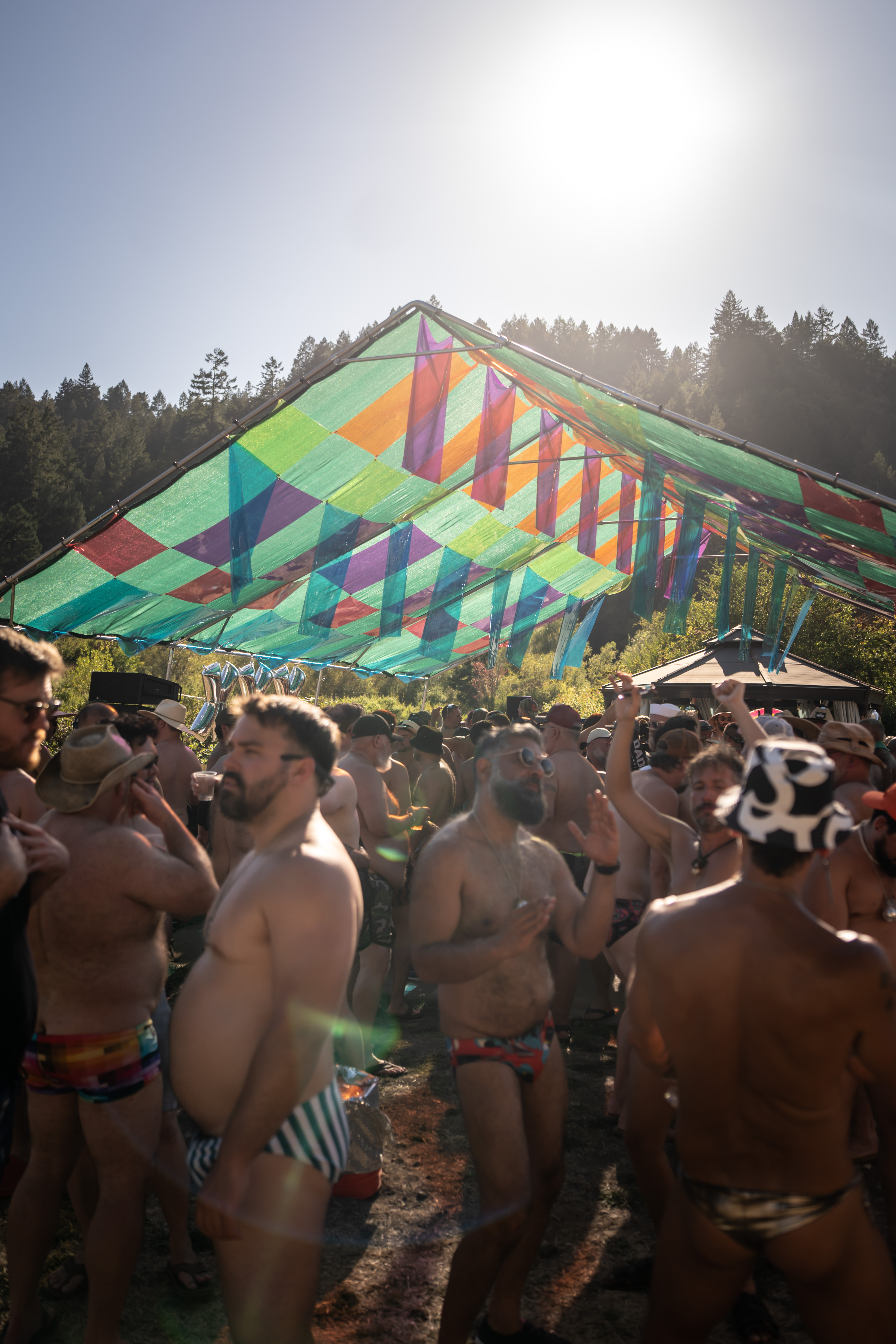 Sun directly behind the canopy peak, crowd dancing beneath